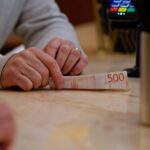 Środkowa sekcja kobiety trzymającej papierową walutę przy stole