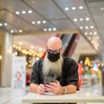 Środkowa część mężczyzny używającego telefonu komórkowego siedzącego na stole