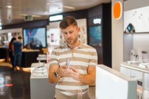 Mężczyzna badający smartfon w sklepie technologicznym