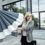 Blond kobieta biznesu otworzyć parasol na tle biura firmy. Czekam na deszcz
