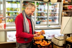 Mężczyzna kupujący w supermarkecie wybierający mandarynki