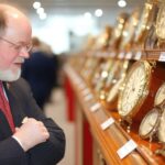 Dżentelmen bada klasyczne zegarki na aukcji przedmiotów kolekcjonerskich w tętniącej życiem sali wystawienniczej