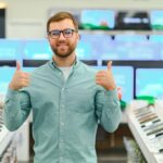 Mężczyzna stoi w pobliżu telefonów komórkowych w sklepie z elektroniką