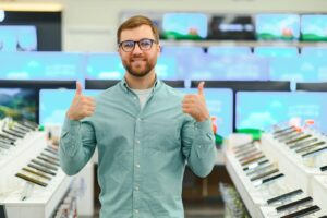 Mężczyzna stoi w pobliżu telefonów komórkowych w sklepie z elektroniką