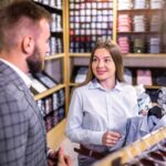 Asystent konsultantka dziewczyna oferuje różnorodne koszule w wersji męskiej