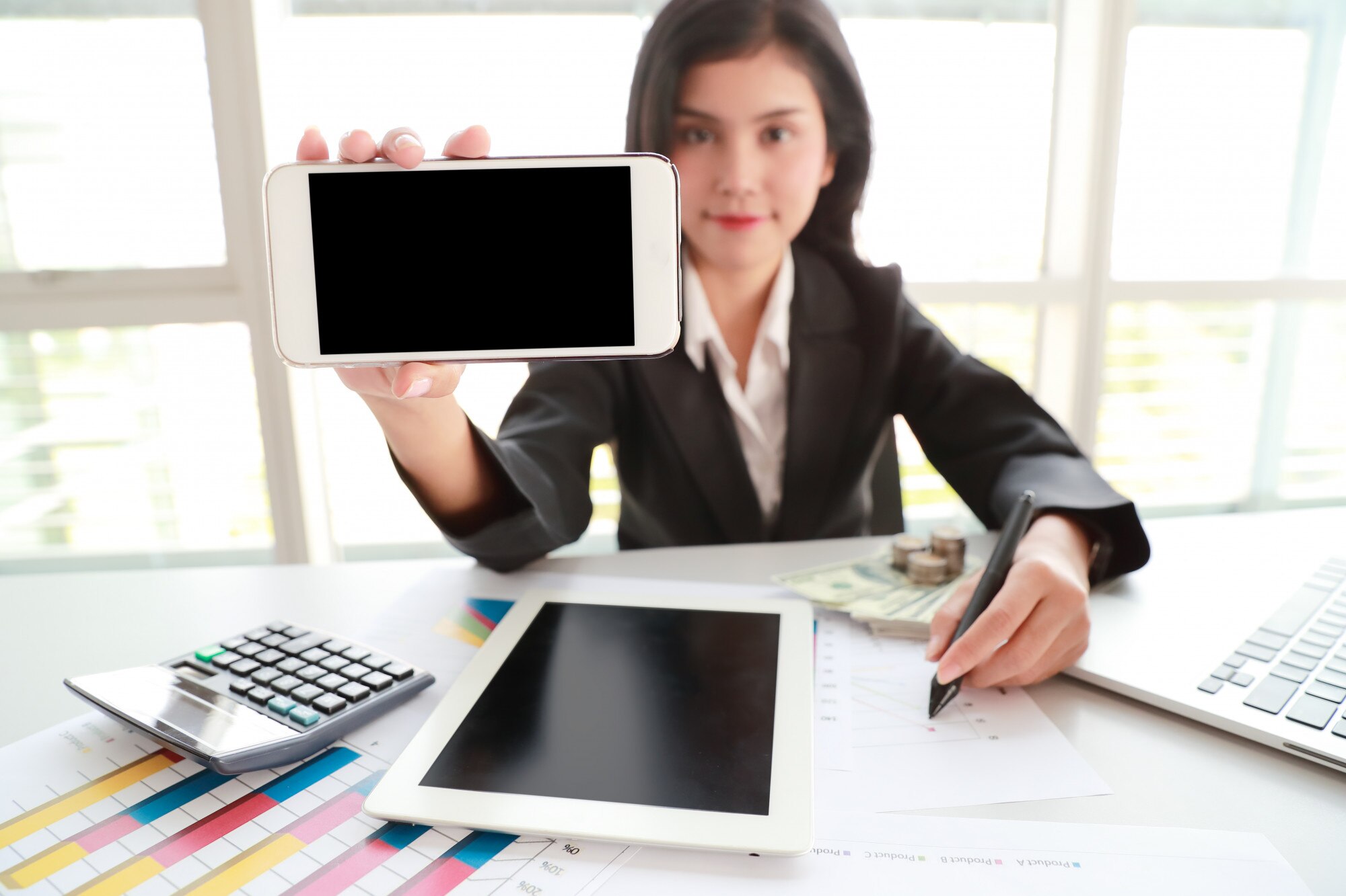 Bizneswoman pokazuje pustego ekranu telefon komórkowego z pastylką na stole