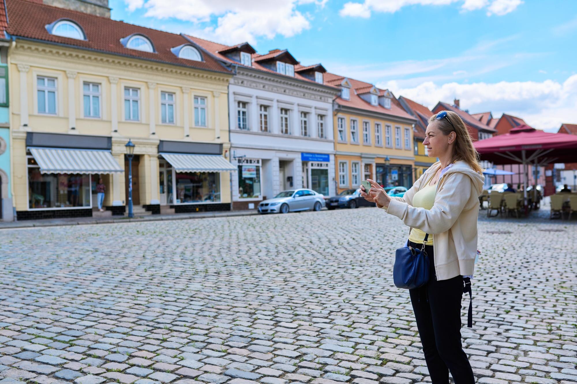 Kobieta turystka robi zdjęcie w starym europejskim mieście przed zabytkowym budynkiem Kobieta podróżująca przez Niemcy za pomocą smartfona do robienia zdjęć Koncepcja architektury historii turystyki