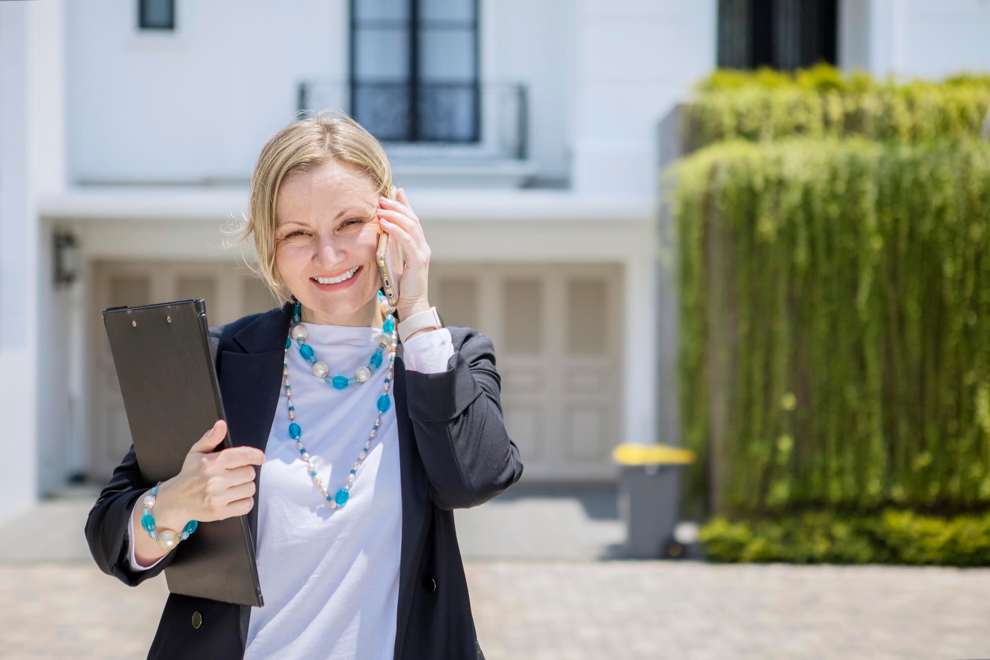 Biały agent nieruchomości rozmawia przez telefon w pobliżu nowego domu.
